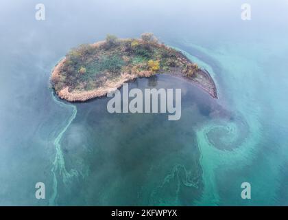 Eine Luftaufnahme einer giftigen blaugrünen Algenblüte (Cyanobakterien), die um eine Insel, Loch Leven, Schottland, wirbelt Stockfoto