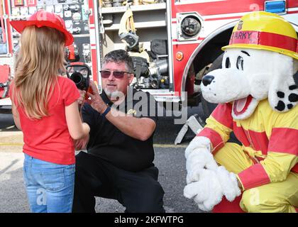 221012-N-UJ449-2065 MARINELUFTSTATION SIGONELLA, ITALIEN (OKT 12, 2022) Feuerinspektor Gene Tatum, zusammen mit Sigonella Fire and Emergency Services, zeigt Kindern während der Fire Prevention Week auf der Marinestützpunkt Sigonella, 12. Oktober 2022, eine Feuerschlauchdüse. Die strategische Lage von NAS Sigonella ermöglicht es US-amerikanischen, alliierten und Partnernationen, ihre Kräfte je nach Bedarf einzusetzen und zu reagieren, um Sicherheit und Stabilität in Europa, Afrika und Central Command zu gewährleisten. Stockfoto