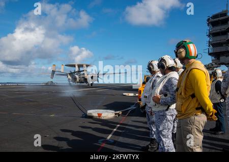 221012-N-JO823-1227 PHILIPPINISCHES MEER (OKT 12, 2022) Matrosen der philippinischen Marine beobachten, wie ein E-2D Hawkeye, der an den Tiger Tails of Airborne Early Warning Squadron (VAW) 125 befestigt ist, auf dem Flugdeck des einzigen vorwärts eingesetzten Flugzeugträgers der US Navy, USS Ronald Reagan (CVN 76), in der philippinischen See landet, 12. Oktober. Ronald Reagan, das Flaggschiff der Carrier Strike Group 5, stellt eine kampfbereite Kraft zur Verfügung, die die Vereinigten Staaten schützt und verteidigt und Allianzen, Partnerschaften und kollektive maritime Interessen in der Indo-Pazifik-Region unterstützt. Stockfoto