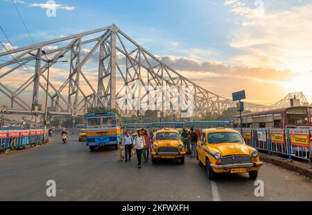 Öffentliche Verkehrsmittel auf der Stadtstraße in der Nähe der historischen Howrah-Brücke Kalkutta, Indien bei Sonnenaufgang. Stockfoto