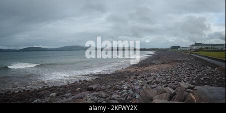 Blick auf den Strand von Waterville, County Kerry, Irland, der unter dem Morgengrauen mit einem dunklen, wolkenverhangenen Himmel im Hintergrund glitzert Stockfoto