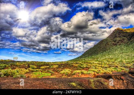 Wolken im blauen Himmel und grüne Felder mit Bergen an einem sonnigen Tag, Nordwestküste von Teneriffa in der Nähe von Punto Teno Leuchtturm, Canarias. Stockfoto