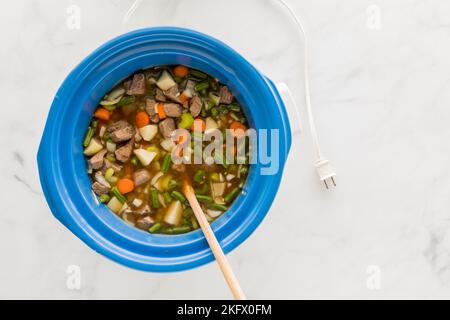 Ein Topftopf gefüllt mit einem hausgemachten Rind- und Gersteneintopf, der zum Kochen bereit ist. Stockfoto