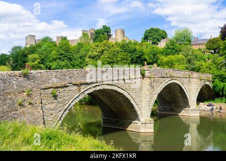 Ludlow Shropshire Ludlow Castle über der Dinham Bridge, die den Fluss Teme überquert, mit Kindern, die im Wasser spielen Ludlow Shropshire England GB Europa Stockfoto