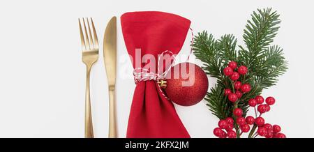 Weihnachtliche Tischkulisse, Festessen. Goldenes Besteck und rote Stoffserviette auf weißem Hintergrund, Draufsicht Stockfoto