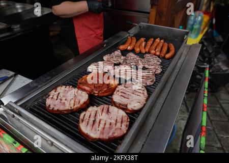 Details zu geringer Schärfentiefe (selektiver Fokus) mit Schweinewurst und Steaks, die auf einem Barbecue-Grill auf einem europäischen Bauernmarkt in Bukarest zubereitet werden Stockfoto