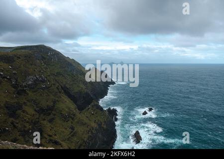 Kerry Klippen mit grünem Gras und dramatischen Wolken am bewölkten Herbsttag, Kerry, Irland. Stockfoto