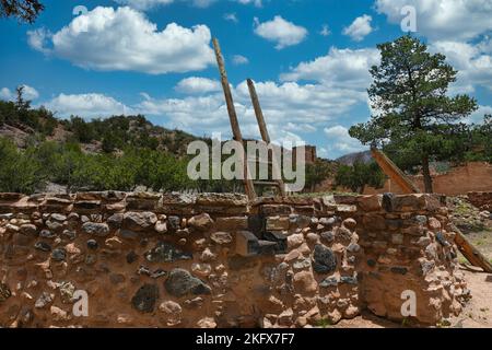 Gíusewa Pueblo Kiva mit den Ruinen der Mission San José de los Jémez im Hintergrund. Stockfoto