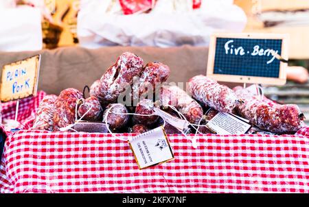 Rot-weiß kleiden Sie sich mit französischen getrockneten Fleischsaucen, Wurst, Salami, gestapelt zum Verkauf an einem Marktstand unter freiem Himmel. Stockfoto