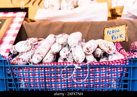 Rot-weiß kleiden Sie sich mit französischen getrockneten Fleischsaucen, Wurst, Salami, gestapelt zum Verkauf an einem Marktstand unter freiem Himmel. Stockfoto