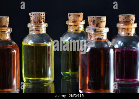 Farbige Ölflaschen auf schwarzem Hintergrund Stockfoto