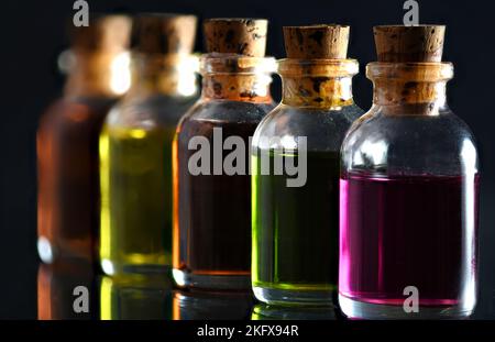 Farbige Ölflaschen auf schwarzem Hintergrund Stockfoto