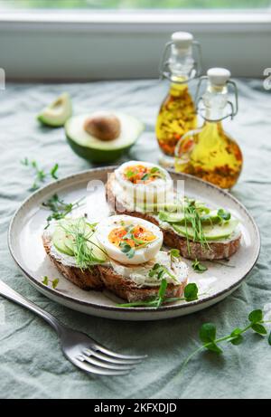 Brottoast, gekochte Eier, Avocado-Scheibe, Mikrogemüse auf einem Teller, Frühstückszeit Stockfoto