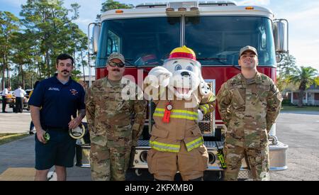 Sparky, der Feuerhund, das offizielle Maskottchen der National Fire Protection Association und Mitglieder der Keesler Fire Department posieren für ein Foto vor einem Feuerwehrauto während der Fire Prevention Week Tour im Child Development Center auf der Keesler Air Force Base, Mississippi, 13. Oktober 2022. Die ganze Woche hindurch führte die Keesler Feuerwehr willkürliche Feuerübungen durch, besichtigte verschiedene Einrichtungen mit Sparky, dem Feuerwehrhund, gab Brandschutzinformationen und Feuermützen für Kinder heraus. Stockfoto