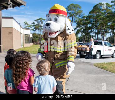 Sparky, der Feuerhund, das offizielle Maskottchen der National Fire Protection Association, begrüßt Kinder aus dem Child Development Center während der Fire Prevention Week Tour im CDC auf dem Keesler Air Force Base, Mississippi, 13. Oktober 2022. Die ganze Woche hindurch führte die Keesler Feuerwehr willkürliche Feuerübungen durch, besichtigte verschiedene Einrichtungen mit Sparky, dem Feuerwehrhund, gab Brandschutzinformationen und Feuermützen für Kinder heraus. Stockfoto