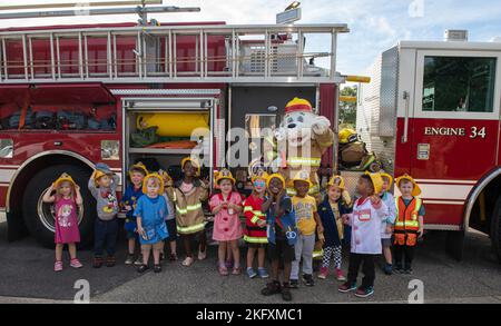 Kinder vom Child Development Center posieren für ein Gruppenfoto mit Sparky, dem Feuerhund, dem offiziellen Maskottchen der National Fire Protection Association, während der Fire Prevention Week Tour im CDC auf dem Keesler Air Force Base, Mississippi, 13. Oktober 2022. Die ganze Woche hindurch führte die Keesler Feuerwehr willkürliche Feuerübungen durch, besichtigte verschiedene Einrichtungen mit Sparky, dem Feuerwehrhund, gab Brandschutzinformationen und Feuermützen für Kinder heraus. Stockfoto