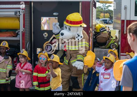 Kinder vom Child Development Center posieren für ein Gruppenfoto mit Sparky, dem Feuerhund, dem offiziellen Maskottchen der National Fire Protection Association, während der Fire Prevention Week Tour im CDC auf dem Keesler Air Force Base, Mississippi, 13. Oktober 2022. Die ganze Woche hindurch führte die Keesler Feuerwehr willkürliche Feuerübungen durch, besichtigte verschiedene Einrichtungen mit Sparky, dem Feuerwehrhund, gab Brandschutzinformationen und Feuermützen für Kinder heraus. Stockfoto