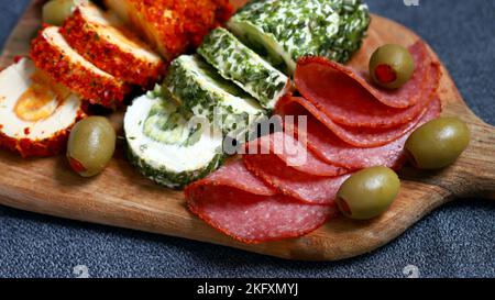 Snacks im italienischen Stil auf einem Holzbrett. Käserollen, Salami, Oliven. Stockfoto