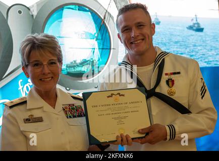 Hinterer Adm. Cynthia Kuehner, Kommandant des Naval Medical Forces Support Command, presnets Hospital Corpsman William T. Ericson die Navy and Marine Corps Medal in Anerkennung für Handlungen des nicht-Kampfheldentums während einer Zeremonie vor kurzem im Navy Medicine Training Support Center. Während einer Wanderung außerhalb des Diensts am Cabrillo National Monument am 2. Mai 2021 beobachtete Ericson ein angeschwemmtes Schiff mit mehr als 30 notleidenden Passagieren in der Nähe der felsigen Küste. Als das Schiff in sechs Fuß hoher See gegen Felsbrocken gestürzt wurde, verließen mehrere Personen das Boot im 60-Grad-Wasser. (US-Navy-Foto) Stockfoto