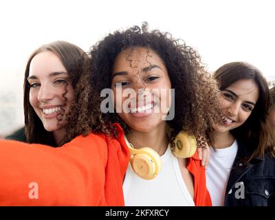 Drei multiethnische junge Freundinnen, die Spaß haben. Selfie-Perspektive Stockfoto