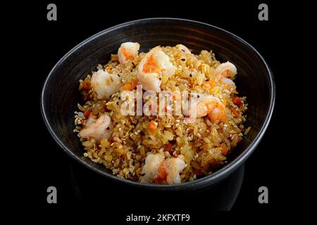 Gebratener Reis mit Garnelen und Sesam, auf dunklem Hintergrund. Panasia Stockfoto