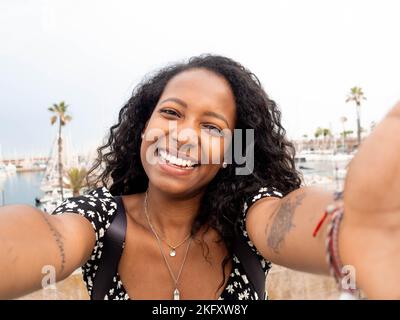 Glückliches Selfie einer lächelnden jungen afroamerikanischen Touristenfrau im Urlaub in einer Stadt Stockfoto