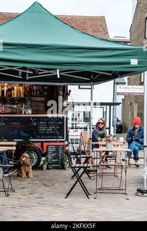 Epsom, Surrey, London, Großbritannien, 19 2022. November, zwei junge Frauen sitzen vor Einem Pop-up-Café oder Café und entspannen sich und unterhalten sich gekleidet für Einen kalten Tag Stockfoto