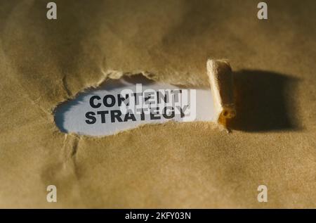 Wirtschafts- und Geschäftskonzept. Zerrissenes Papier in der Mitte des Blattes, innen auf weißem Hintergrund die Aufschrift - INHALTSSTRATEGIE Stockfoto