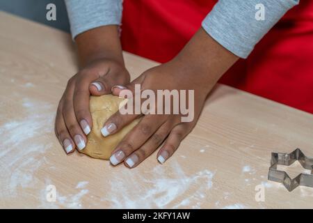 Junge Frau knetet mit den Händen den Teig aus Zimt und Vanillegebäck Stockfoto