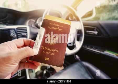 Tourist Hand mit Thailand Pass, Kreditkarte, Covid-19 Negativ-Testband auf einer Hand im Innenraum des Autos mit Sonnenlicht Stockfoto