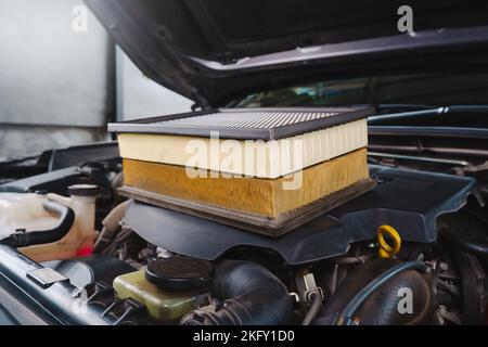 Vergleich von neuen und gebrauchten Autoluftfiltern, die am Motor angebracht sind Stockfoto