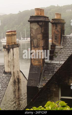 Alte Schornsteine auf alten Häusern über dem Hafen von Tobermory, Mull, Schottland, die alte Ziegelarbeiten und Schieferdächer zeigen Stockfoto