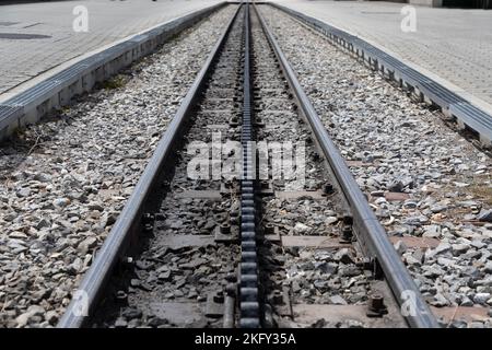 Selektiver Fokus, abnehmende Perspektive Bahngleise mit einer mittleren dritten Zahnradbahn, um die Züge an einem steilen Hang hochzuziehen. Stockfoto