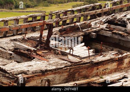 Ein großes, altes, zerstörtes Holzboot im Trockendock, das verrottende Holz, Muttern und Bolzen und Metall zeigt, da es langsam abschwächt Stockfoto
