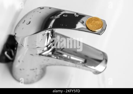 20-Euro-Cent-Münze auf einem Wasserhahn im Bad. Sparsamer Wasserverbrauch konzeptionelle Idee. Sparkonzept für Haushaltsbudgets. Stockfoto