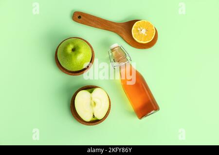 Zusammensetzung mit einer Flasche Apfelessig und frischen Früchten auf farbigem Hintergrund Stockfoto