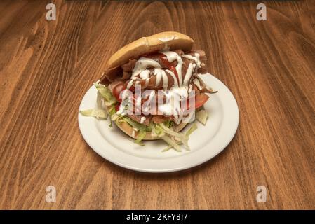 Typischer Teller mit Kebab-Sandwich mit gemischtem Lammfleisch mit Huhn, weißer Zwiebel und Salat und Tomaten und viel Sauce Stockfoto