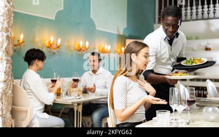 Der Kellner brachte die Bestellung zur Dame im Restaurant Stockfoto