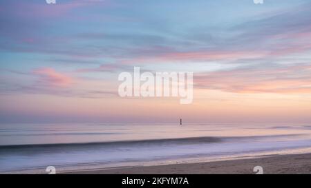 Schöner Sonnenuntergang am Meer. Ein isolierter Leuchtturm, der vor dem Ufer steht. rivedoux Strand auf der Insel Ré Stockfoto