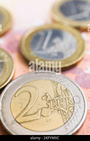 Zwei- und eine-Euro-Münzen auf zehn Euro-Banknoten in Papierwährung. Stockfoto