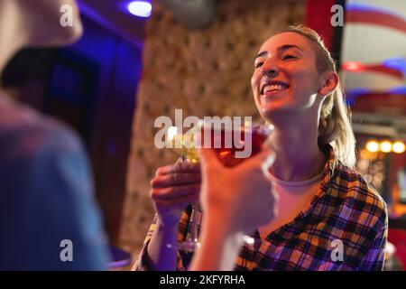 Zwei fröhliche weiße Freundinnen in einer Bar, trinken Cocktails und reden Stockfoto