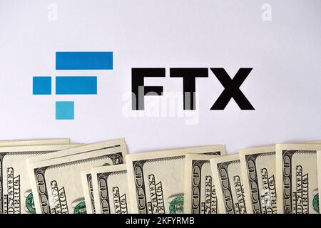 FTX Cryptocurrency Exchange-Logo auf Papier gedruckt und US-Dollar-Banknoten um ihn herum. Konzept für Firmenbankrott und Schulden. Stafford, United Kindom Stockfoto