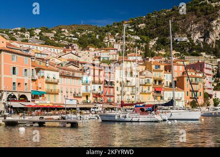 Farbenfrohe Fassaden von Hotel- und Apartmentgebäuden und Hafen mit verankerten Segelbooten und Sportbooten, Villefranche-sur-Mer, Provence, Frankreich. Stockfoto