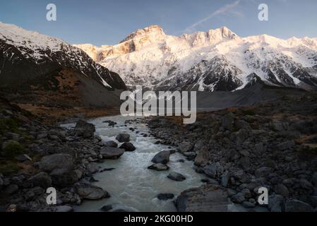 Der Hooker River führt den Weg zum Mueller Lake und mit Mount Sefton oben, der das aufsteigende Morgenlicht erhaschen kann. Stockfoto