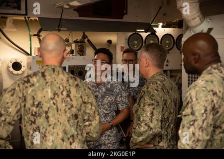 POLARIS POINT, Guam (Okt 18, 2022) – Hospital Corpsman 3. Klasse Christopher Dodge, zugewiesen an das U-Boot-Tender USS Emory S. Land (AS 39), Zentrum, Er schaut in die Tauchkammer der Emergent Repair Facility, während er Mitgliedern der Republic of Singapore Navy (RSN) während der RSN- und U.S. Navy Submarine Force Staff Talks von 4., Oktober 18, ihre Fähigkeiten erklärt. Seit 2017 haben diese Unterseeboot-Gespräche Führer sowohl der US- als auch der RSN-U-Boot-Streitkräfte zusammengebracht, um über die verstärkte Interoperabilität und den Aufbau von Beziehungen zu diskutieren. Stockfoto