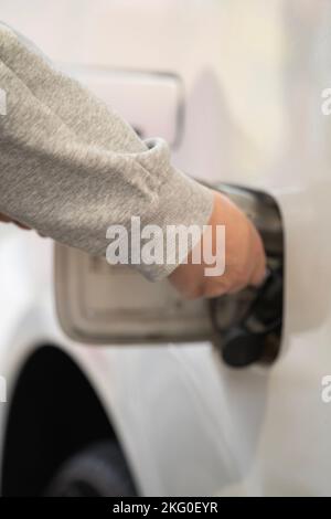 Nahaufnahme des Tankdeckels eines von der Hand öffnenden Autos in einem weißen Auto. Tanken eines Autos an einer Tankstelle. Stockfoto