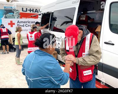 Fort Myers Beach, FL, USA--10/19/22--Ein Freiwilliger der Spirituellen Pflege des Roten Kreuzes betet mit einer Frau an einem Verteilungspunkt am Fort Myers Beach. Jocelyn Augustino/FEMA Stockfoto