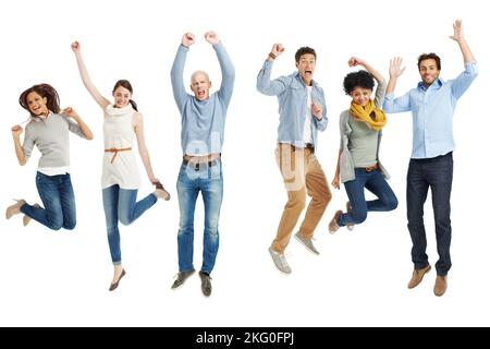 Wir feiern den Moment. Gruppe von lässig gekleideten jungen Erwachsenen, die aufgeregt vor weißem Hintergrund springen. Stockfoto