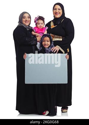 Wir haben viel zu sagen. Studioportrait der weiblichen Mitglieder einer muslimischen Familie, die ein leeres, auf Weiß isoliertes Schild hochhält. Stockfoto