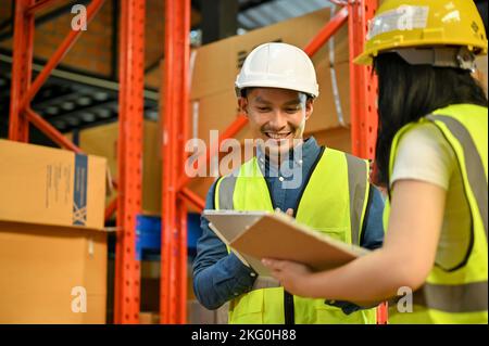 Professioneller männlicher Lagerleiter aus Asien, der im Millennial-Bereich mit einer Arbeiterin im Lager arbeitet. Stockfoto